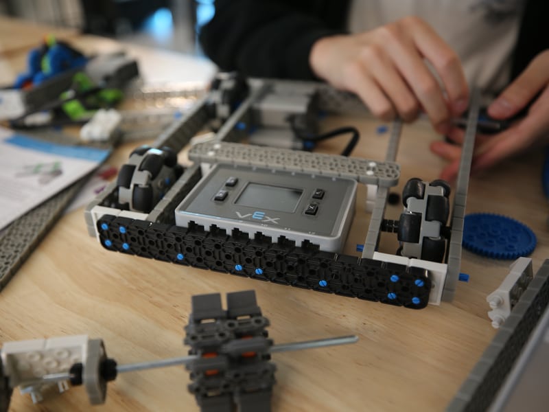 Hands assembling a VEX robot on a workshop table